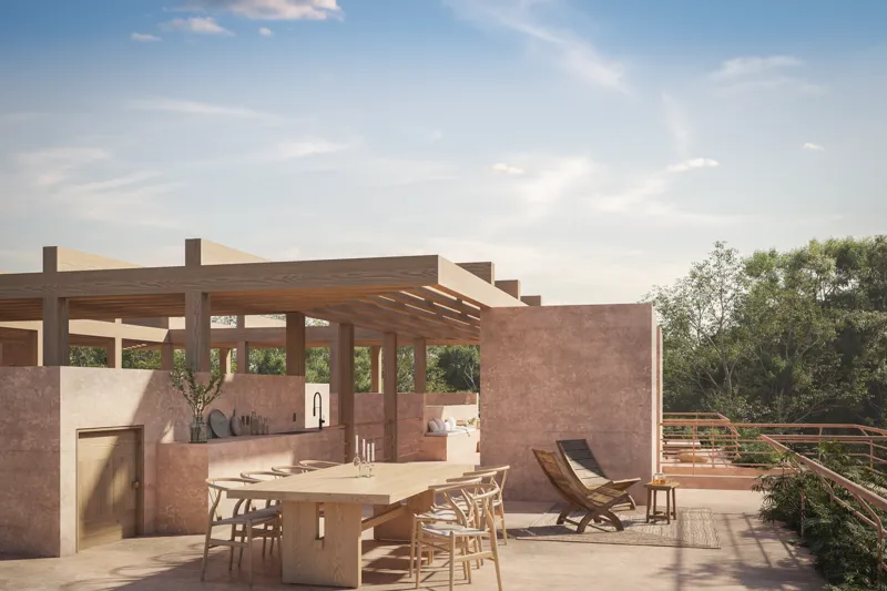 A high-angle render of a spacious outdoor rooftop terrace at Aldea Kalan, featuring a long wooden dining table with chairs, an integrated outdoor kitchen/bar area, and a wooden lounge chair on a light-colored patio, all under a clear blue sky with...