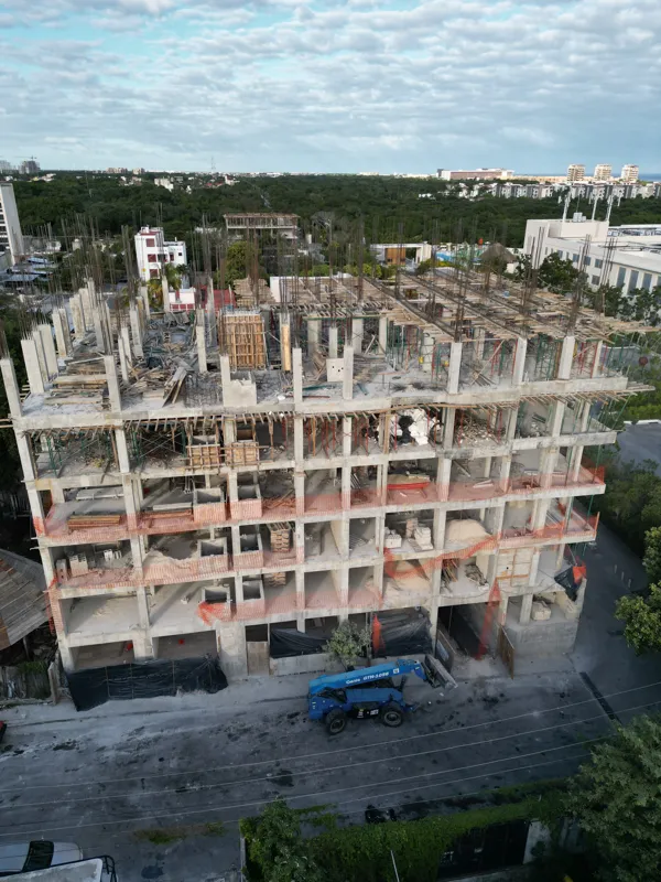 Aerial view of the Maia development showing a multi-story concrete structure under construction. The building has several completed concrete slabs, with extensive wooden formwork and rebar visible on the upper levels, particularly for the 6th floo...