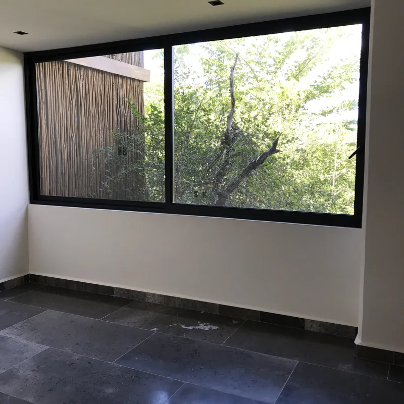 A series of interior photographs from Humana's finished model units, featuring dark grey tiled floors, white walls, wooden built-in furniture, a modern kitchen with stainless steel appliances, and balconies offering views of lush tropical vegetation.