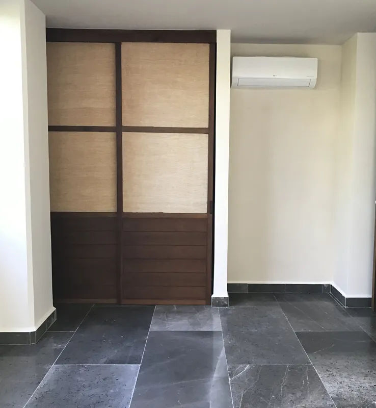 A series of interior photographs from Humana's finished model units, featuring dark grey tiled floors, white walls, wooden built-in furniture, a modern kitchen with stainless steel appliances, and balconies offering views of lush tropical vegetation.