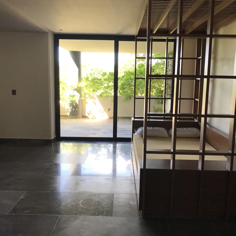 A series of interior photographs from Humana's finished model units, featuring dark grey tiled floors, white walls, wooden built-in furniture, a modern kitchen with stainless steel appliances, and balconies offering views of lush tropical vegetation.