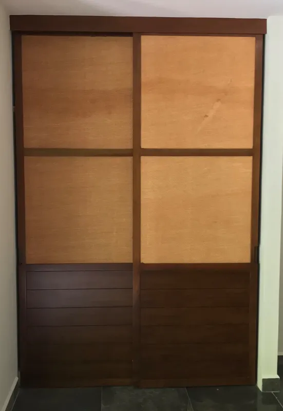 Interior view of a finished residential unit at Humana Tulum, featuring dark polished marble floors, white walls, a built-in wooden closet with sliding doors, an air conditioning unit, and a modern bathroom with a unique stone basin, black fixture...