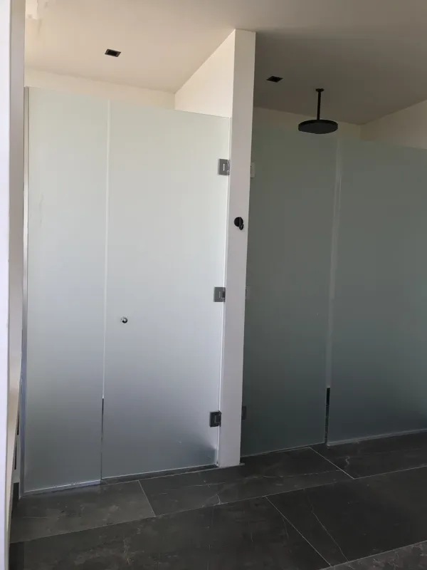 Interior view of a finished residential unit at Humana Tulum, featuring dark polished marble floors, white walls, a built-in wooden closet with sliding doors, an air conditioning unit, and a modern bathroom with a unique stone basin, black fixture...