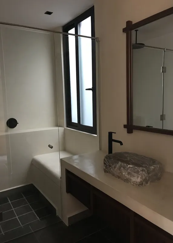 A modern kitchen in Humana's Unit 303D, featuring dark grey upper cabinets, wooden lower cabinets, a black sink, an integrated oven, and a stainless steel refrigerator with protective tape, all set against dark tiled flooring.