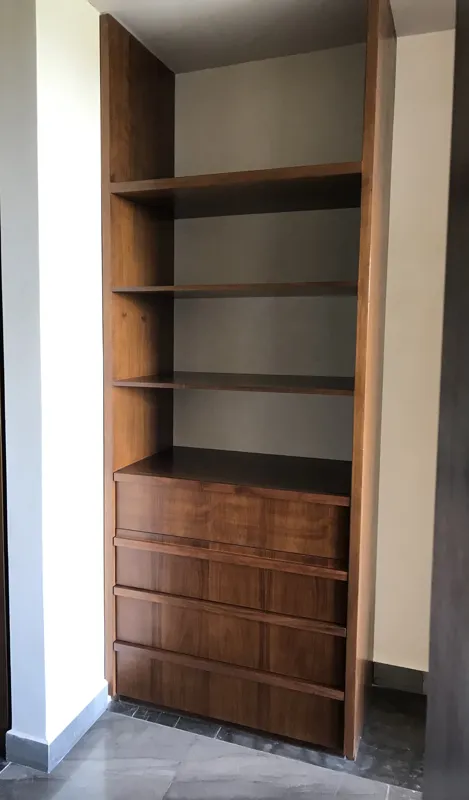 A modern kitchen in Humana's Unit 303D, featuring dark grey upper cabinets, wooden lower cabinets, a black sink, an integrated oven, and a stainless steel refrigerator with protective tape, all set against dark tiled flooring.