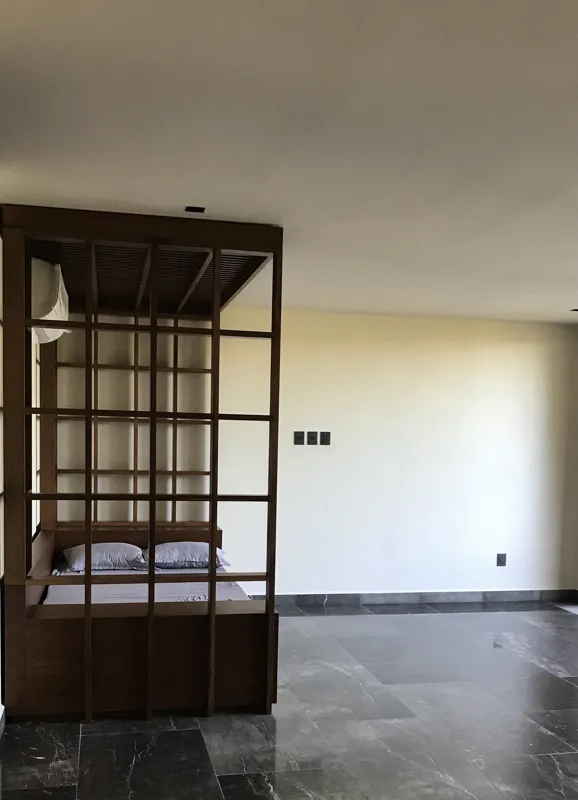 A modern kitchen in a Humana unit featuring dark grey upper cabinets, dark wood lower cabinets, a black countertop, a stainless steel refrigerator, and a breakfast bar, all set against dark tiled floors.