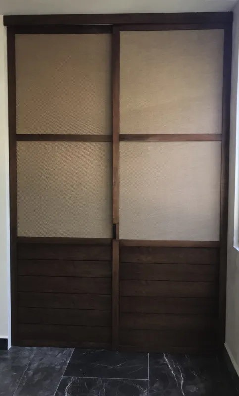A modern kitchen in a Humana unit featuring dark grey upper cabinets, dark wood lower cabinets, a black countertop, a stainless steel refrigerator, and a breakfast bar, all set against dark tiled floors.