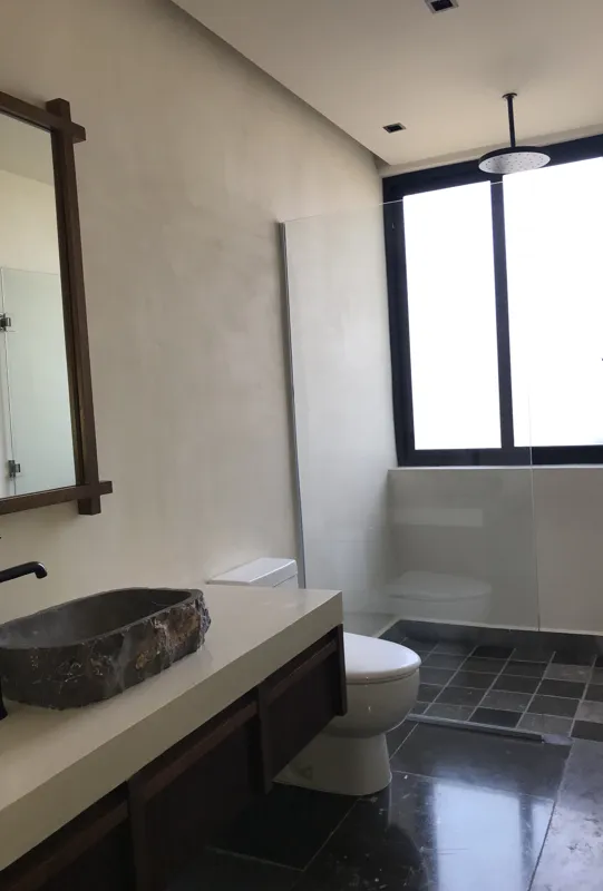 A modern kitchen in a Humana unit featuring dark grey upper cabinets, dark wood lower cabinets, a black countertop, a stainless steel refrigerator, and a breakfast bar, all set against dark tiled floors.