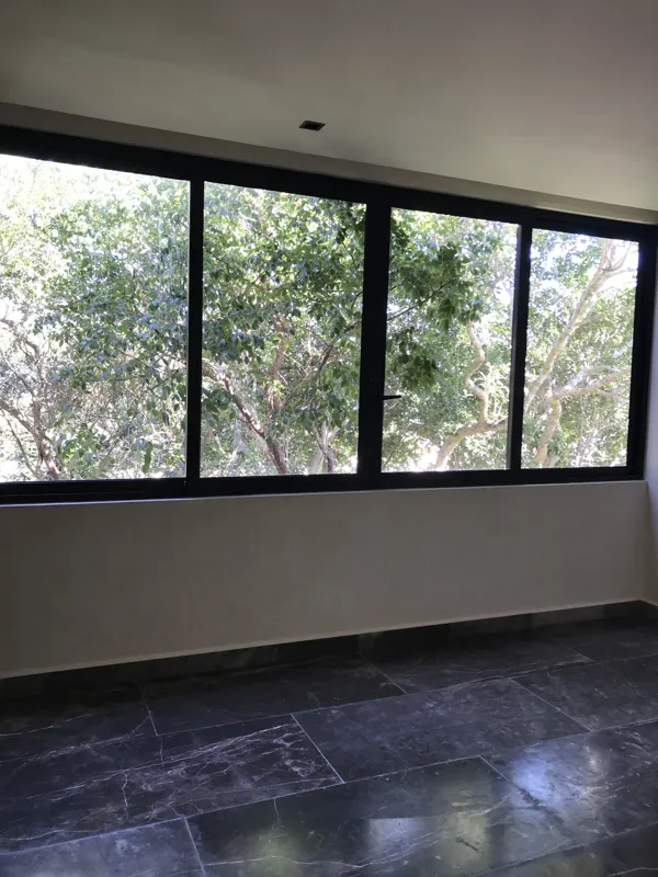 A modern kitchen in a Humana unit featuring dark grey upper cabinets, dark wood lower cabinets, a black countertop, a stainless steel refrigerator, and a breakfast bar, all set against dark tiled floors.
