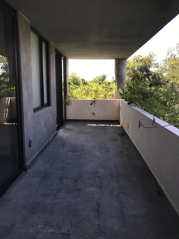 A collection of interior photos from Humana development, featuring a modern bathroom with a unique stone vessel sink, dark wood vanity, and rain shower, alongside a spacious living area with polished grey tiled floors, white walls, and large slidi...