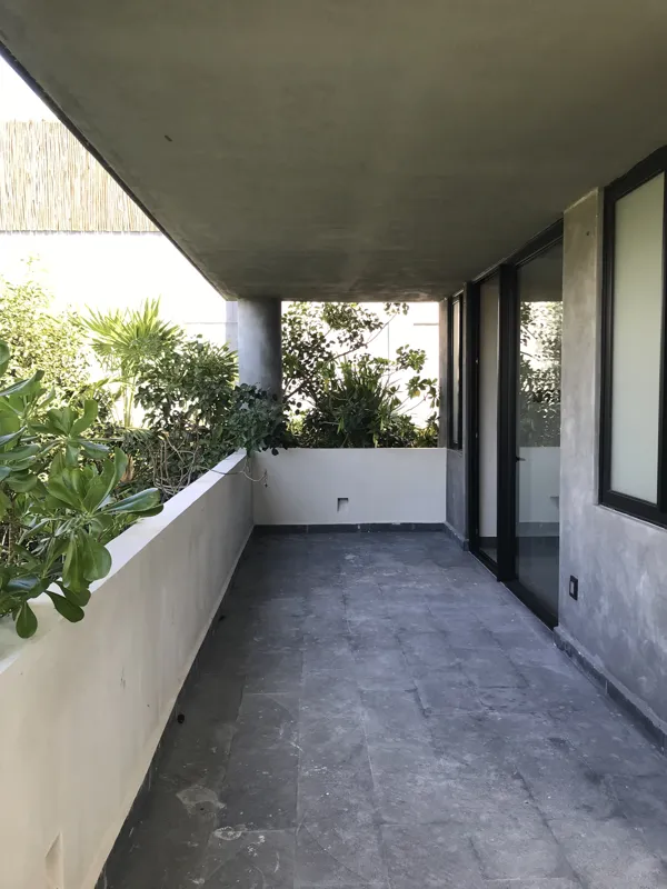 A collection of interior photos from Humana development, featuring a modern bathroom with a unique stone vessel sink, dark wood vanity, and rain shower, alongside a spacious living area with polished grey tiled floors, white walls, and large slidi...