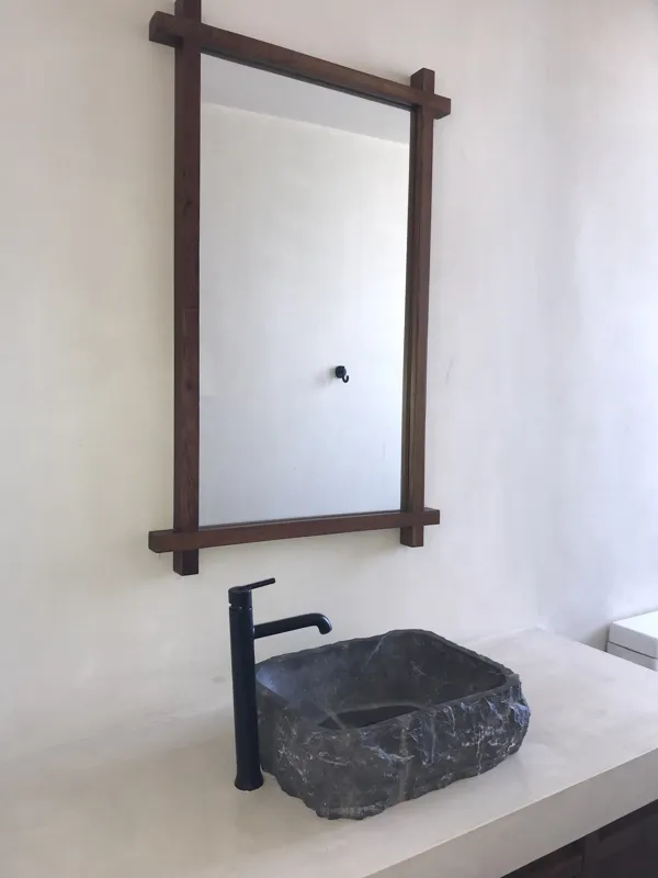 A collection of images showcasing the finished interiors of a Humana model unit, including a contemporary kitchen with dark cabinets and an island, a living area with dark marble floors and a built-in wooden daybed, and a bathroom with a unique st...