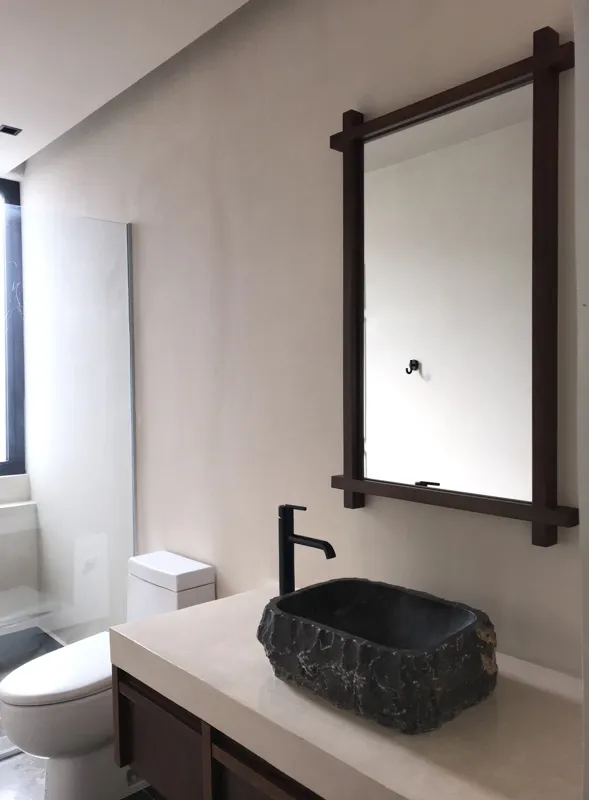 A collection of images showcasing the finished interiors of a Humana model unit, including a contemporary kitchen with dark cabinets and an island, a living area with dark marble floors and a built-in wooden daybed, and a bathroom with a unique st...