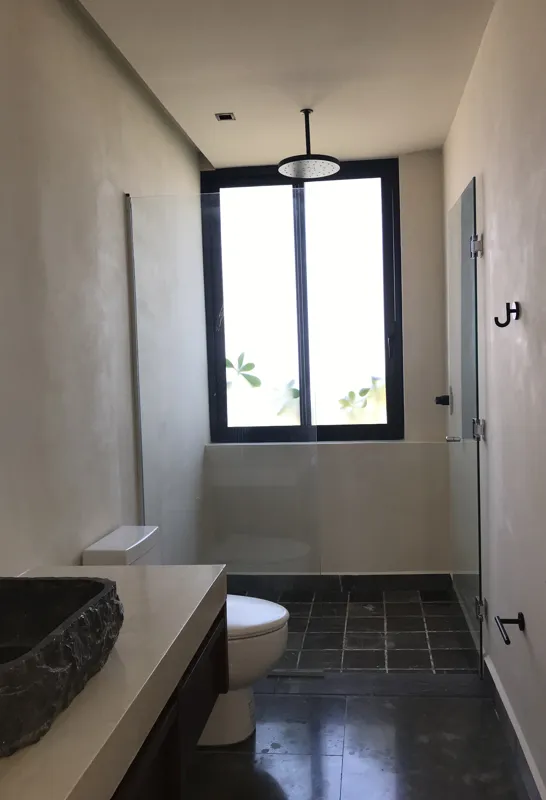 A collection of images showcasing the finished interiors of a Humana model unit, including a contemporary kitchen with dark cabinets and an island, a living area with dark marble floors and a built-in wooden daybed, and a bathroom with a unique st...