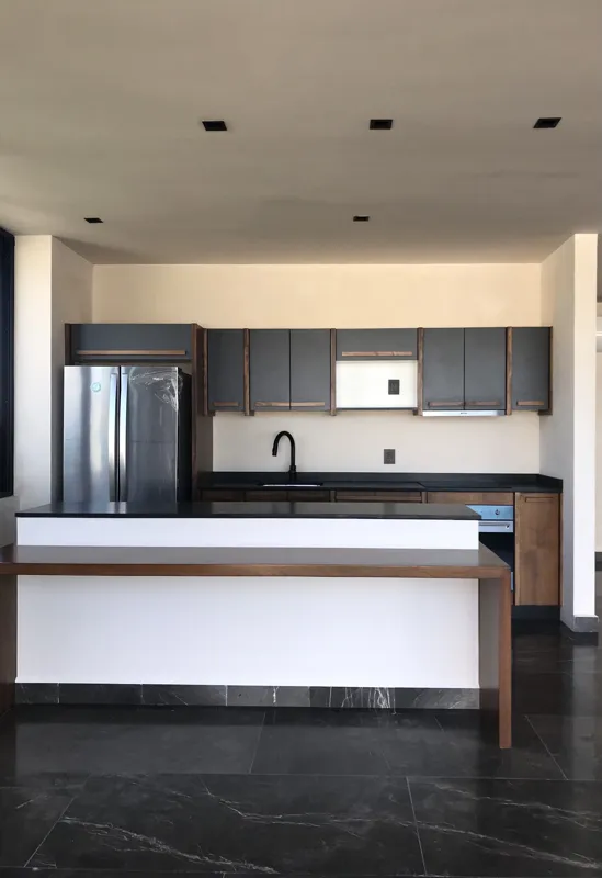 A collection of images showcasing the finished interiors of a Humana model unit, including a contemporary kitchen with dark cabinets and an island, a living area with dark marble floors and a built-in wooden daybed, and a bathroom with a unique st...