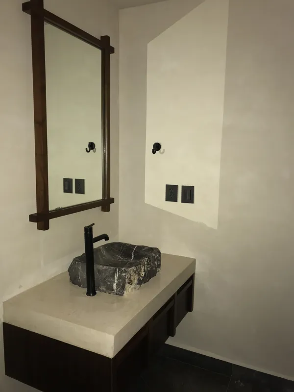 A luxurious rooftop terrace at Humana featuring a built-in jacuzzi with wooden steps, surrounded by modern architecture and lush greenery under a clear blue sky, showcasing finished outdoor amenities.