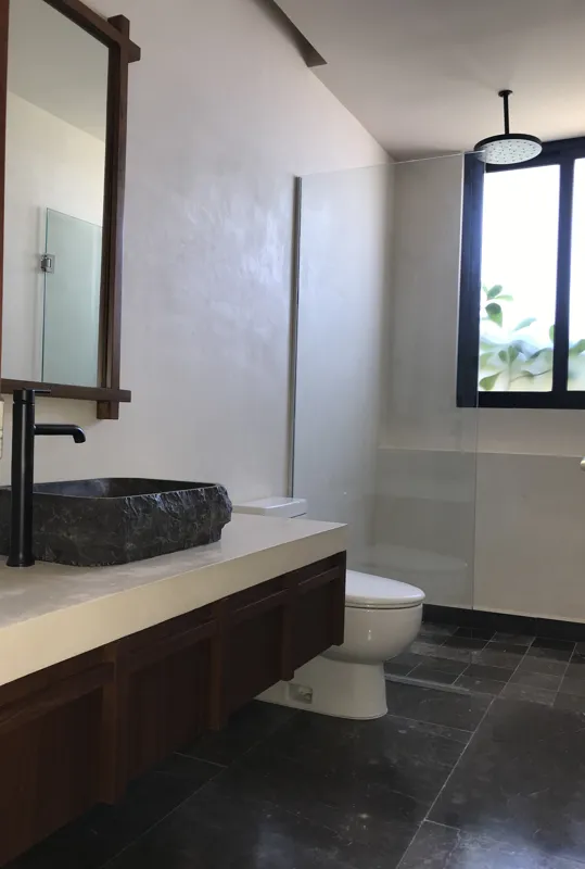 A luxurious rooftop terrace at Humana featuring a built-in jacuzzi with wooden steps, surrounded by modern architecture and lush greenery under a clear blue sky, showcasing finished outdoor amenities.