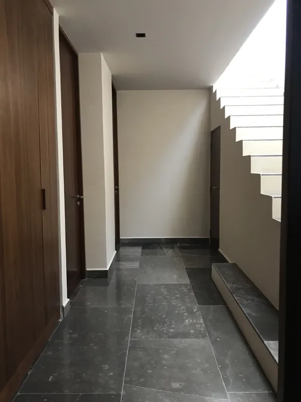 A luxurious rooftop terrace at Humana featuring a built-in jacuzzi with wooden steps, surrounded by modern architecture and lush greenery under a clear blue sky, showcasing finished outdoor amenities.