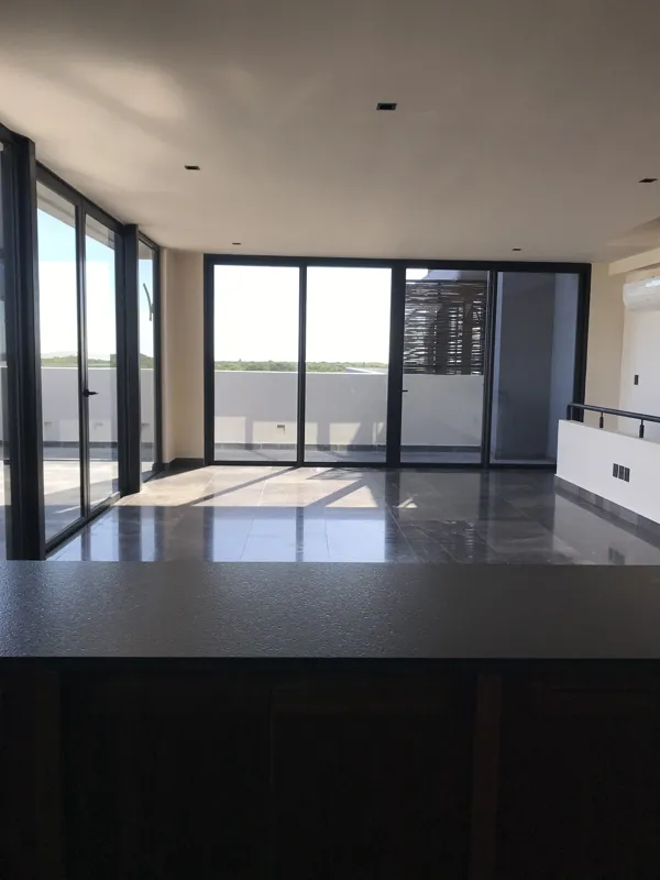 A luxurious rooftop terrace at Humana featuring a built-in jacuzzi with wooden steps, surrounded by modern architecture and lush greenery under a clear blue sky, showcasing finished outdoor amenities.