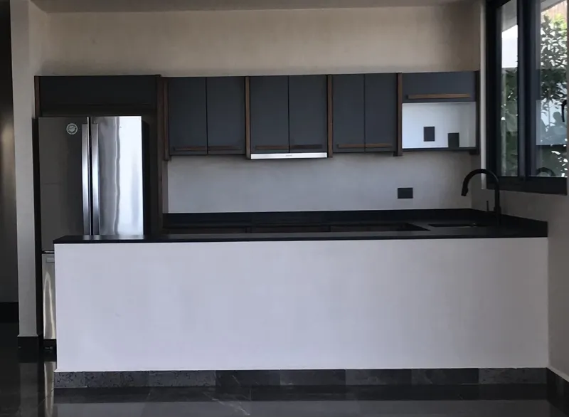 A luxurious rooftop terrace at Humana featuring a built-in jacuzzi with wooden steps, surrounded by modern architecture and lush greenery under a clear blue sky, showcasing finished outdoor amenities.