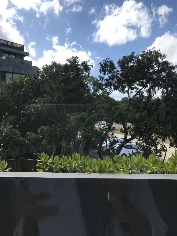 A wide interior shot of a finished residential unit at Humana, featuring dark grey marble-patterned floor tiles, a modern kitchen with dark cabinetry, a central wooden island, and a refrigerator wrapped in protective plastic, indicating a complete...