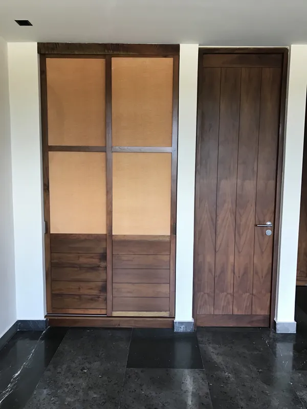 A wide interior shot of a finished residential unit at Humana, featuring dark grey marble-patterned floor tiles, a modern kitchen with dark cabinetry, a central wooden island, and a refrigerator wrapped in protective plastic, indicating a complete...