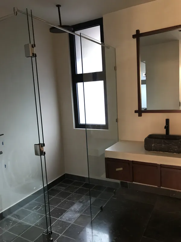 A wide interior shot of a finished residential unit at Humana, featuring dark grey marble-patterned floor tiles, a modern kitchen with dark cabinetry, a central wooden island, and a refrigerator wrapped in protective plastic, indicating a complete...