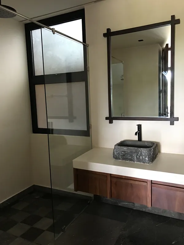 A wide interior shot of a finished residential unit at Humana, featuring dark grey marble-patterned floor tiles, a modern kitchen with dark cabinetry, a central wooden island, and a refrigerator wrapped in protective plastic, indicating a complete...