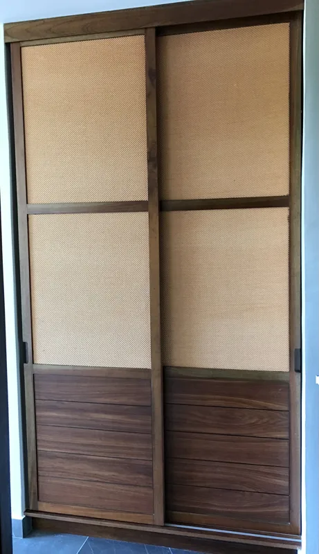 A modern bathroom vanity featuring a dark stone vessel sink, a black faucet, and a rectangular mirror with a dark wooden frame, set above a light-colored countertop and dark wood cabinetry.