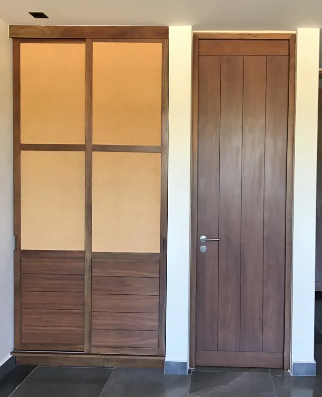 A modern bathroom vanity featuring a dark stone vessel sink, a black faucet, and a rectangular mirror with a dark wooden frame, set above a light-colored countertop and dark wood cabinetry.