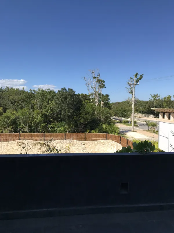 A modern bathroom vanity featuring a dark stone vessel sink, a black faucet, and a rectangular mirror with a dark wooden frame, set above a light-colored countertop and dark wood cabinetry.