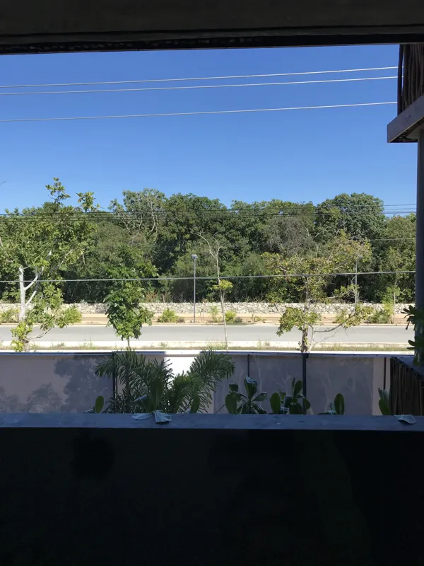 A modern bathroom vanity featuring a dark stone vessel sink, a black faucet, and a rectangular mirror with a dark wooden frame, set above a light-colored countertop and dark wood cabinetry.