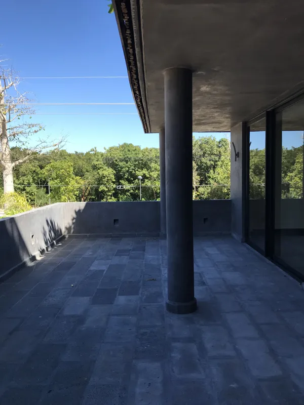 A modern bathroom vanity featuring a dark stone vessel sink, a black faucet, and a rectangular mirror with a dark wooden frame, set above a light-colored countertop and dark wood cabinetry.