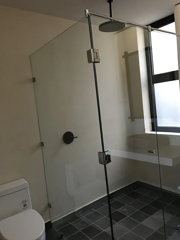 A modern bathroom vanity featuring a dark stone vessel sink, a black faucet, and a rectangular mirror with a dark wooden frame, set above a light-colored countertop and dark wood cabinetry.