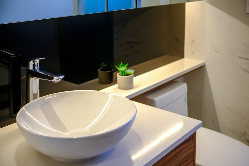 A beautifully furnished living room and balcony in a Woha residence, featuring modern decor, comfortable seating, and a coffee table with pastries, overlooking the Puerto Cancún skyline, a lush golf course, and distant natural reserve.