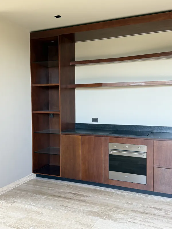 A close-up shot of a modern, brushed brass gooseneck faucet with a single lever handle, set against a dark, speckled countertop and a dark grey backsplash, indicating high-quality interior finishes in an Arthouse Signature apartment.