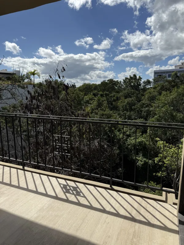 A close-up shot of a modern, brushed brass gooseneck faucet with a single lever handle, set against a dark, speckled countertop and a dark grey backsplash, indicating high-quality interior finishes in an Arthouse Signature apartment.