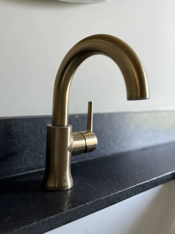 A bright, finished interior room in an Arthouse Signature one-bedroom apartment, featuring light-colored tiled floors, light grey walls, an installed air conditioning unit, and a large sliding glass door opening to a private balcony with lush gree...