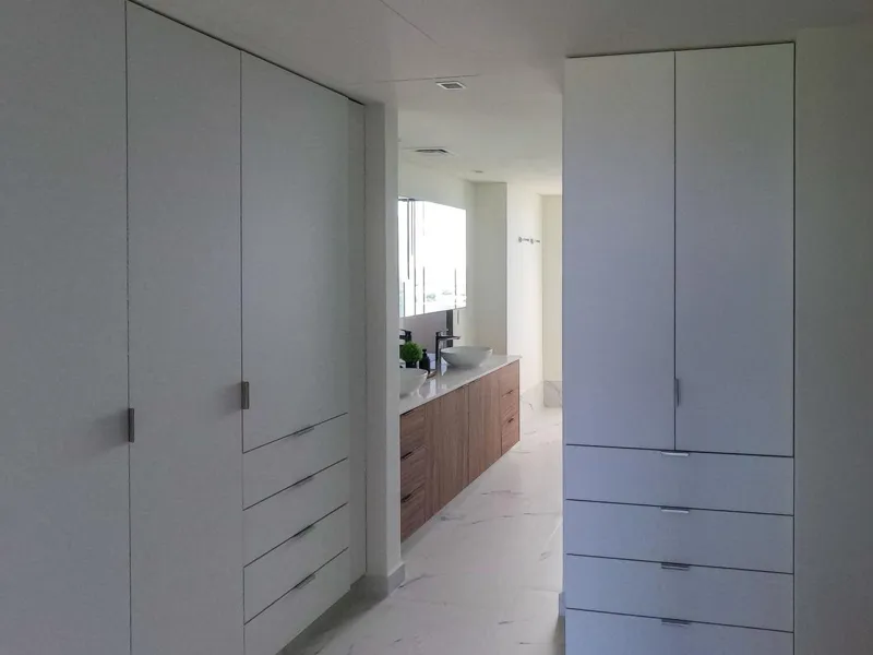 A spacious, elegantly furnished living room in a Woha residence, featuring modern decor, marble floors, and large sliding glass doors opening to a private terrace with panoramic views of the natural reserve, golf course, and distant Caribbean Sea.