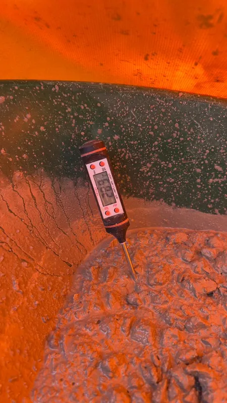 An elevated view of the Abund construction site in Riviera Maya, showing a large white 'Parma' concrete pump truck with its boom extended, actively pouring concrete into a vast, newly formed structural slab. Numerous construction workers in safety...