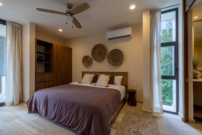 An interior view of Constelada's 1-bedroom model unit, showcasing a modern living and dining area. The space features a light grey sofa with decorative pillows, a sculptural white coffee table, and a round wooden dining table with four light grey ...