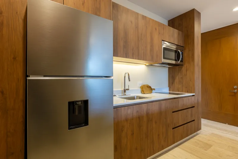 An interior view of Constelada's 1-bedroom model unit, showcasing a modern living and dining area. The space features a light grey sofa with decorative pillows, a sculptural white coffee table, and a round wooden dining table with four light grey ...