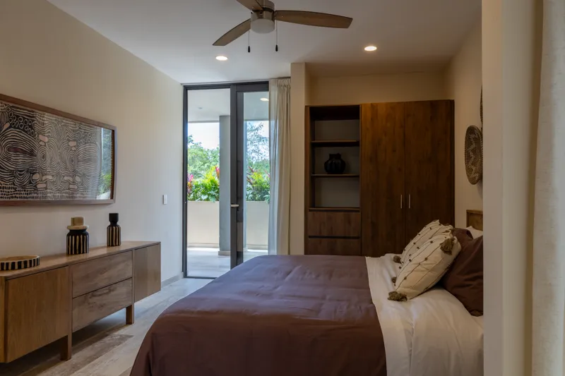 An interior view of Constelada's 1-bedroom model unit, showcasing a modern living and dining area. The space features a light grey sofa with decorative pillows, a sculptural white coffee table, and a round wooden dining table with four light grey ...