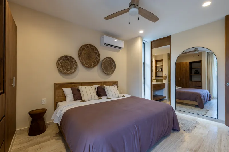 An interior view of Constelada's 1-bedroom model unit, showcasing a modern living and dining area. The space features a light grey sofa with decorative pillows, a sculptural white coffee table, and a round wooden dining table with four light grey ...