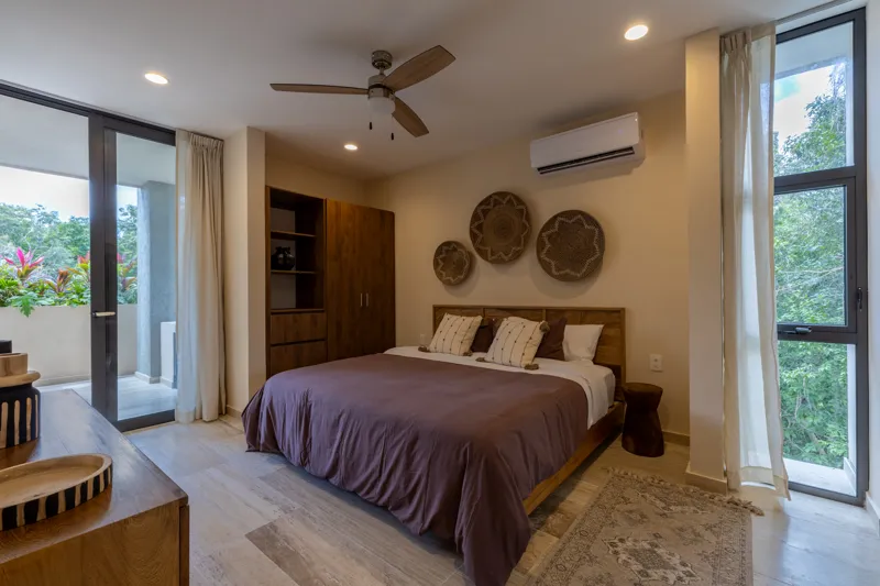 An interior view of Constelada's 1-bedroom model unit, showcasing a modern living and dining area. The space features a light grey sofa with decorative pillows, a sculptural white coffee table, and a round wooden dining table with four light grey ...