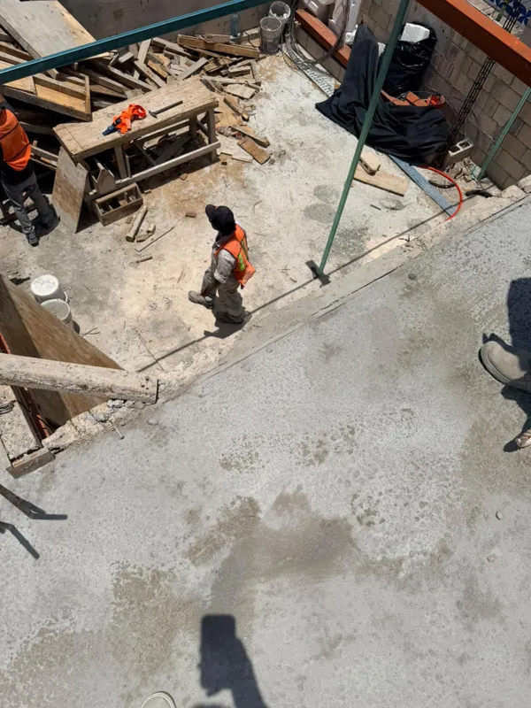 Panoramic view from the newly completed upper-level concrete slab at Ola de Mar, showcasing the urban landscape of Playa del Carmen, including a large commercial building, and the distant Caribbean Sea under a blue sky with white clouds. Construct...