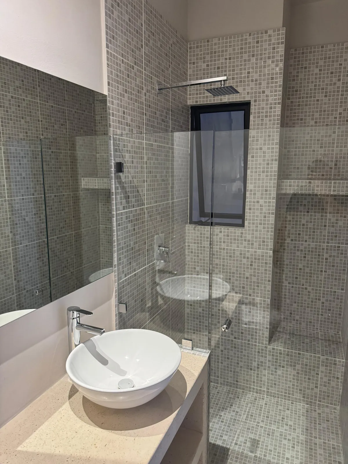 Modern bathroom with grey mosaic tiles and glass shower