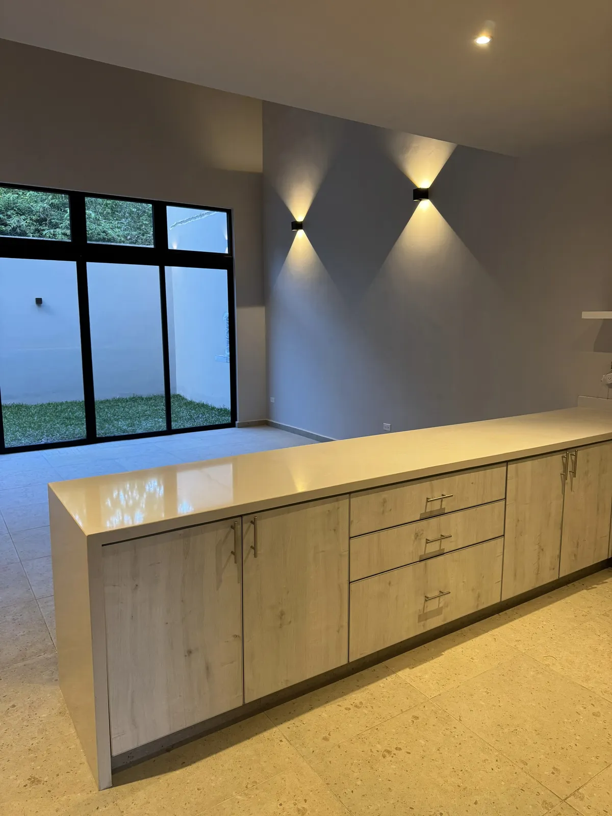 Modern kitchen island with light wood cabinets and wall sconces