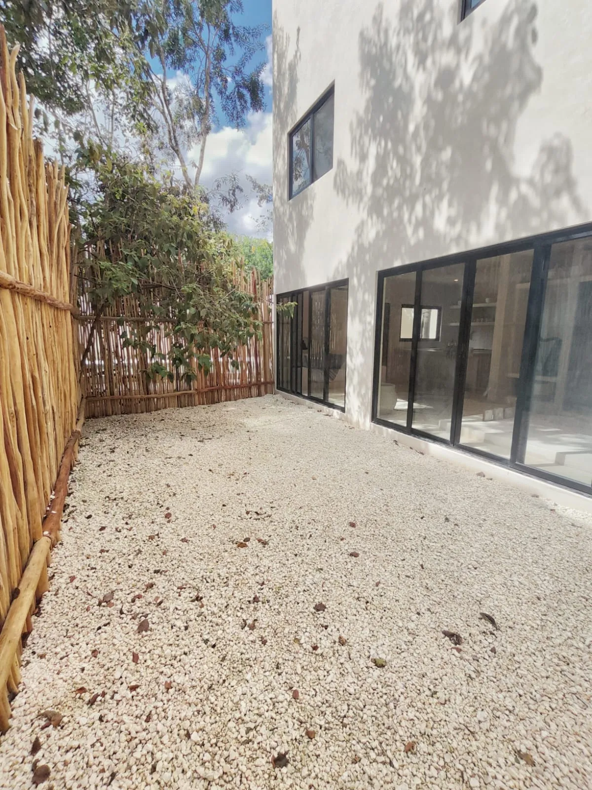 Gravel yard next to white house with wooden fence