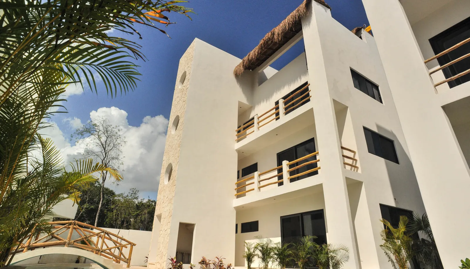 Modern white building exterior with wooden railings and tropical plants